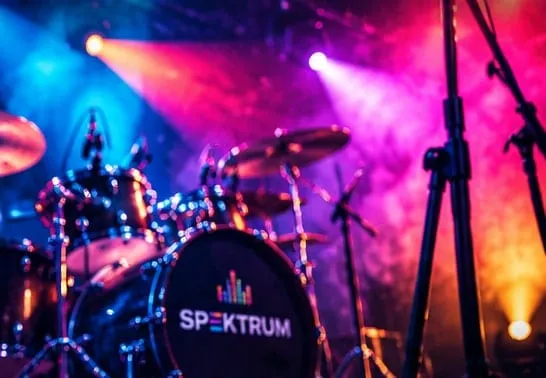 Perkusja z logo SPEKTRUM na scenie w różowych i niebieskich światłach
